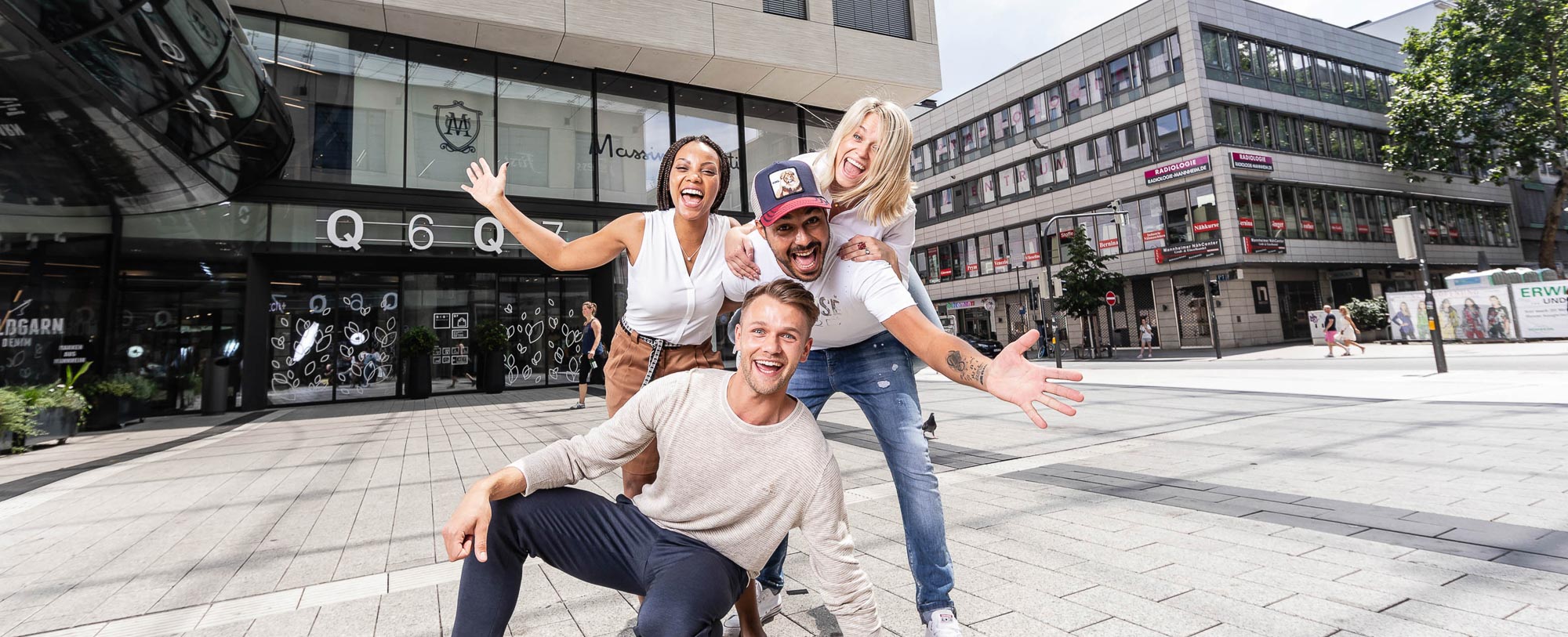 Dieses Bild zeigt vier Personen, die fröhlich auf dem Münzplatz zusammen lächeln. 